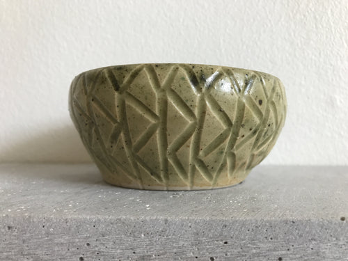 Rund lerpotte med mønster på siderne